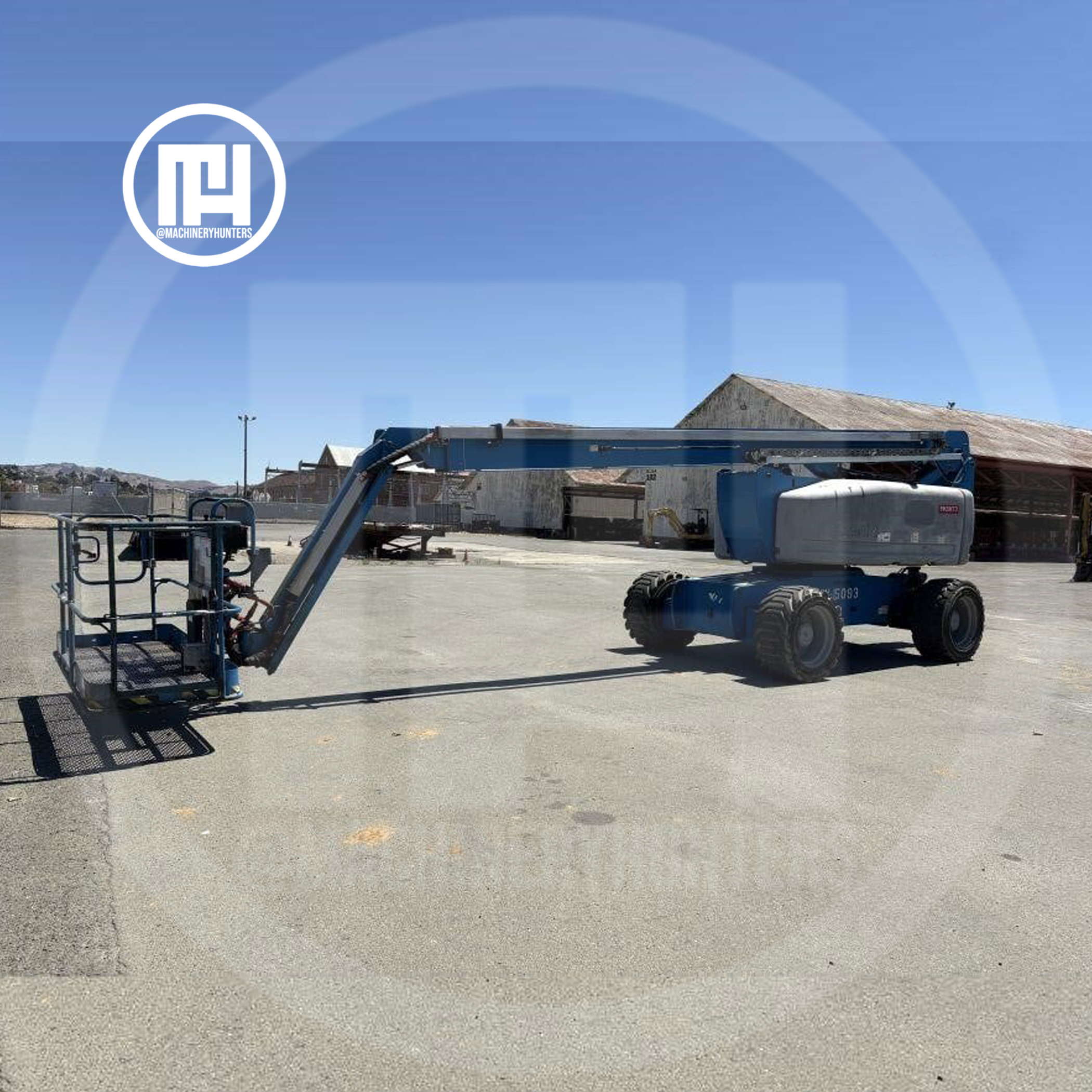 Elevador articulado Genie Z-80/60 2015 extendido en operación en patio industrial.