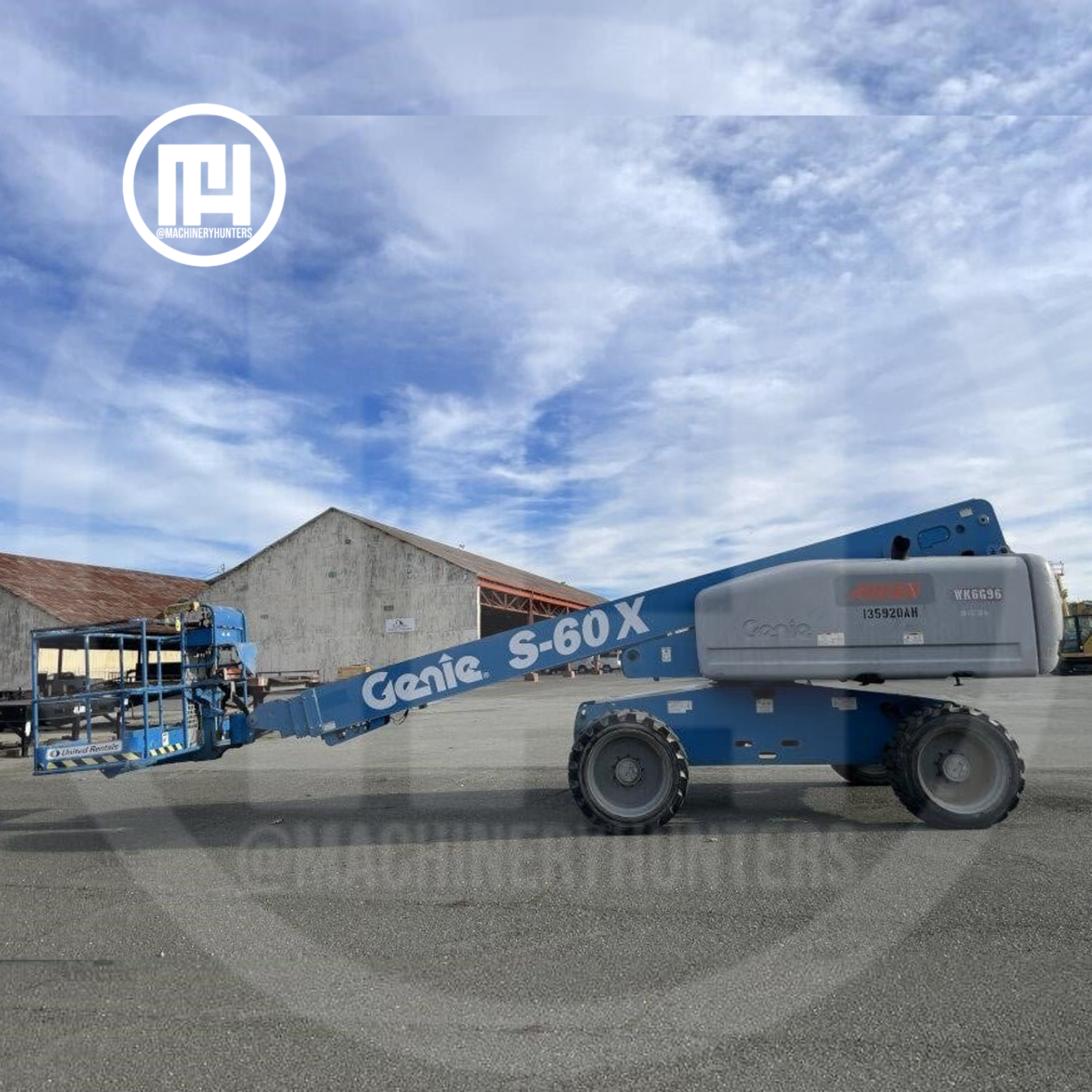 Elevador telescópico Genie S-60X 2014 con brazo completamente extendido frente a nave industrial.