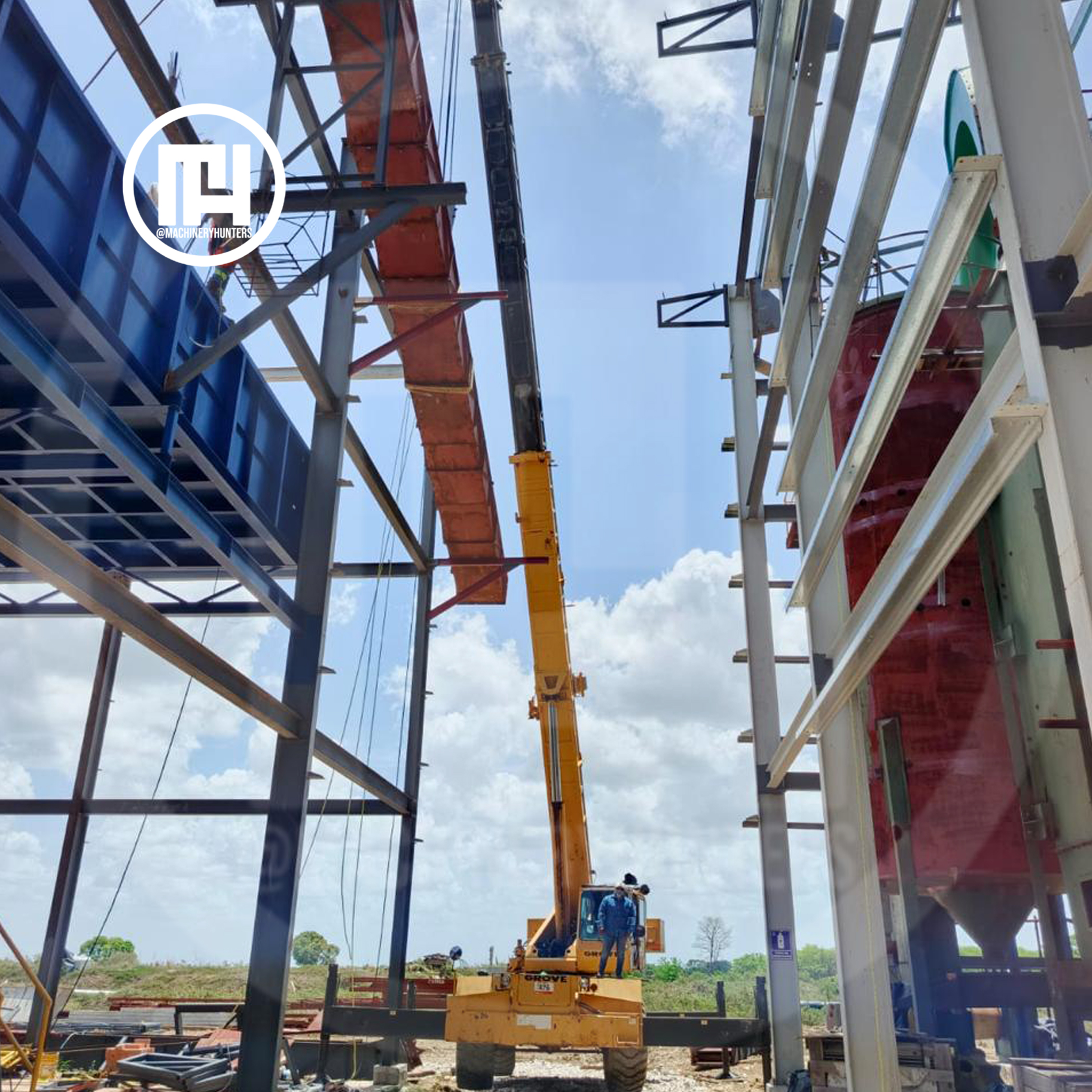 Grúa Grove RT740 elevando viga en estructura metálica industrial