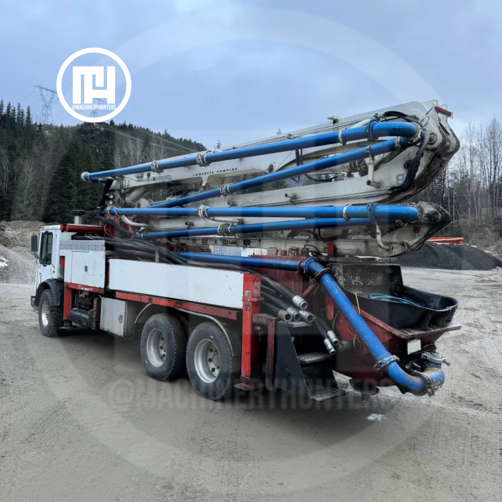 Vista trasera de camión con bomba de concreto Putzmeister de 32 metros en posición de transporte, tubería visible.