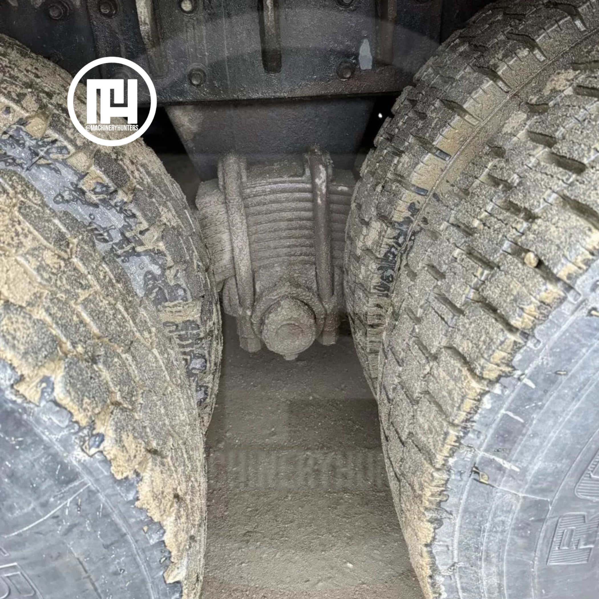 Vista cercana del eje y doble llanta trasera de camión MACK, con tierra de obra.
